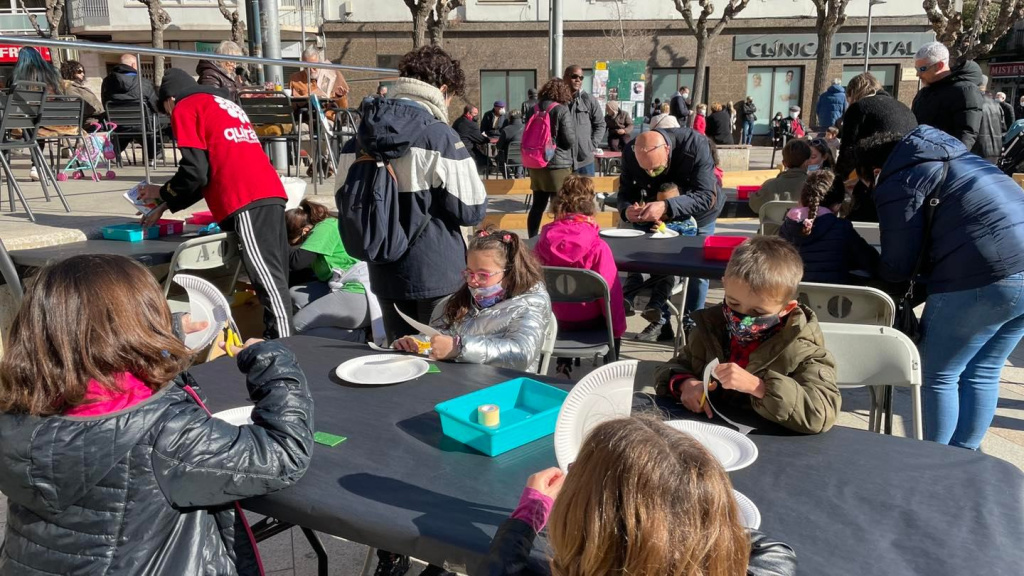 Infants fent activitats amb les mans a les taules preparades de la Plaça de la Sardana.