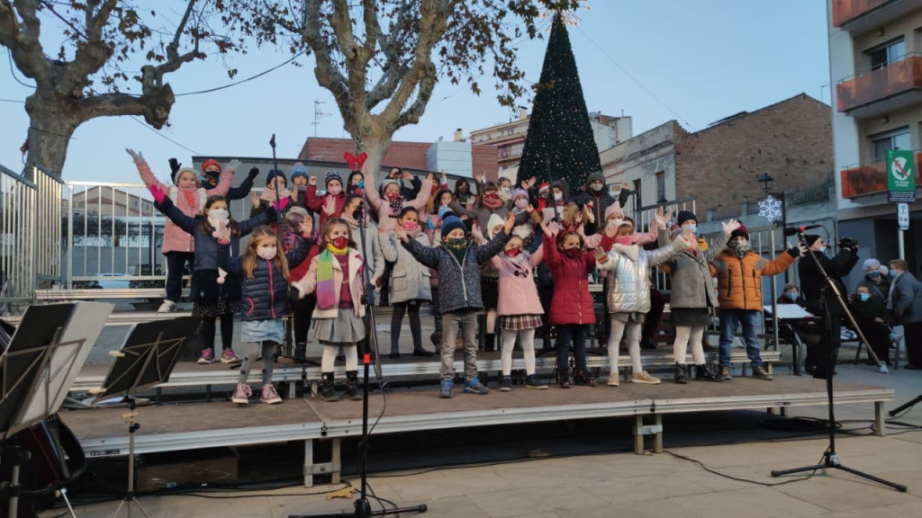 Escenari a la plaça de l'ajuntament amb tots els nens i nenes amb mascaretes, alumnes de l'Escola de Música, fent l'actuació