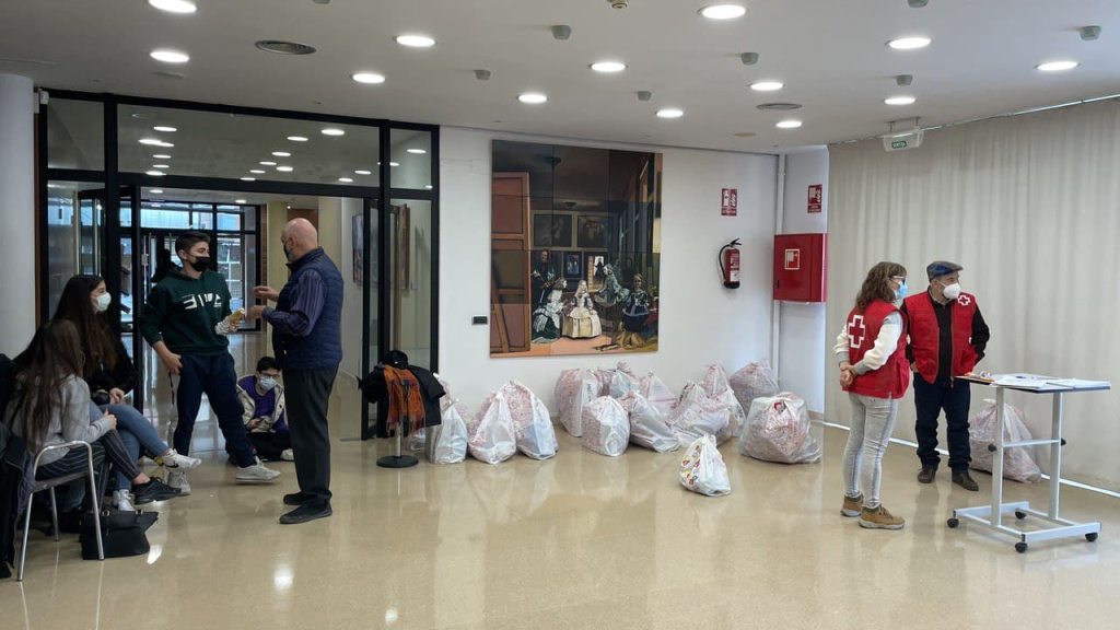 Nois i noies voluntaris en la casa de cultura amb personal de la Creu Roja amb el lliurament de bosses de joguines