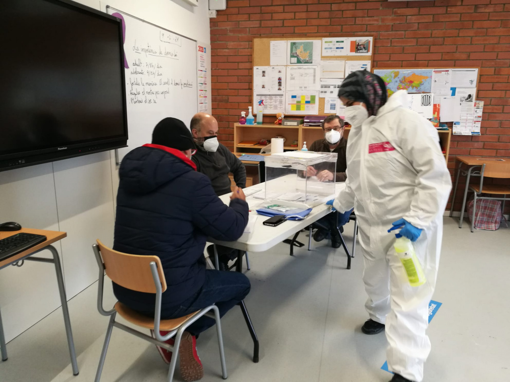 Mesa de votacions amb personal de l'escola fent desinfecció